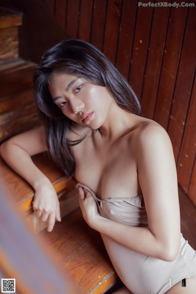 A woman in a brown dress sitting on a wooden staircase.
