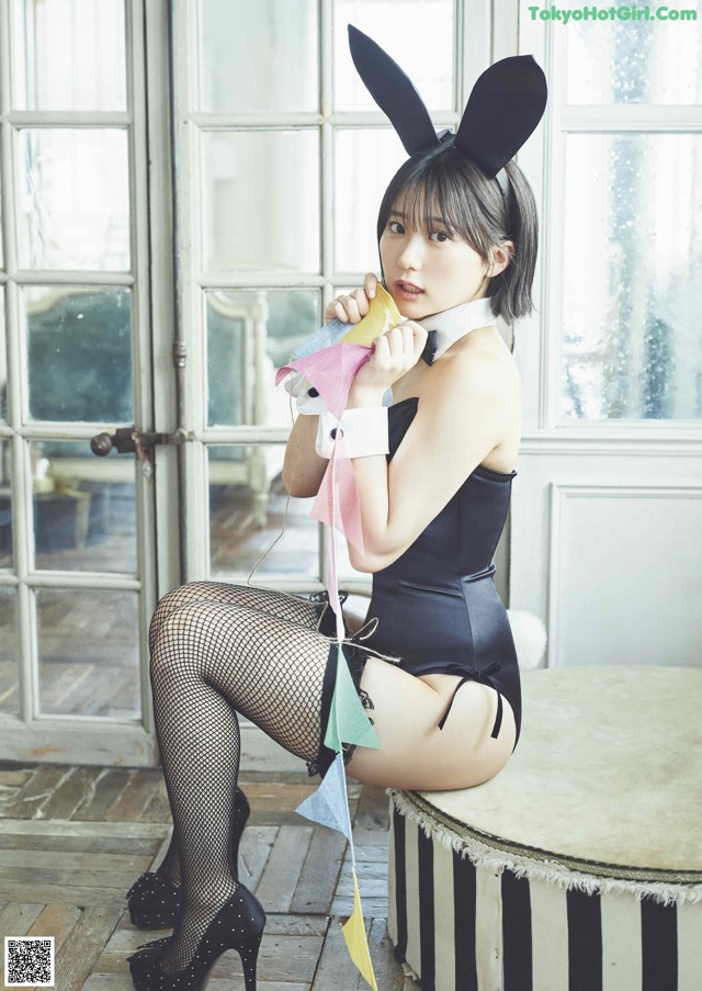 A woman in a bunny costume sitting on a stool.
