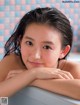 A young woman sitting in a bathtub with her hand on her chin.