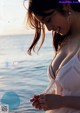 A woman in a white dress standing by the water.