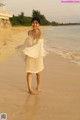 A woman standing on a beach next to the ocean.