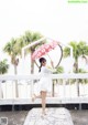 A woman in a white dress holding an umbrella.