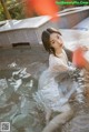 A woman in a white dress sitting in a pool of water.