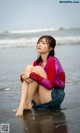 A woman sitting on the beach with her legs crossed.