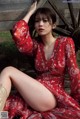 A woman in a red dress sitting on a wooden bench.