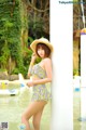 A woman in a yellow and white bathing suit and a straw hat.