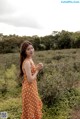 A woman in an orange polka dot dress standing in a field.