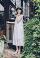 A woman in a white dress standing in front of a door.