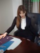 A woman sitting at a desk in a business suit.