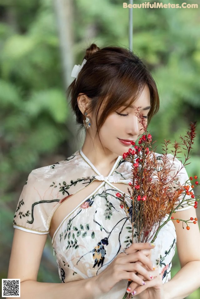 A woman in a white dress holding a bunch of flowers.