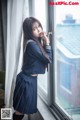 A woman in a school uniform leaning against a window.