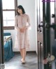 A woman standing in front of a door wearing a pink dress.