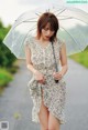 A woman in a dress holding an umbrella in the rain.